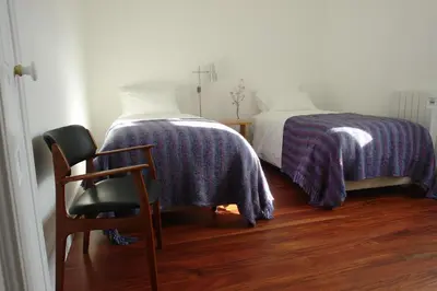 a bedroom with a bed and a chair with a blanket at Casas Adentro in Faro