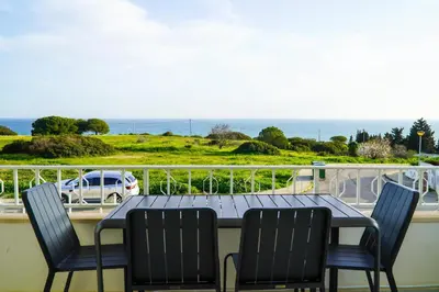 a table and chairs on a balcony with a view of the ocean at Apartamento Bernard in Albufeira