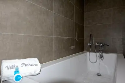 a bathroom with a bath tub with a shower and a towel at Villa Pinheiro CD 84 - Cleverdetails in Vilamoura