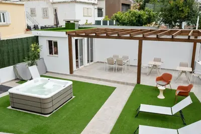 a patio with a hot tub and chairs on the grass at Urban Bliss Guesthouse II in Faro