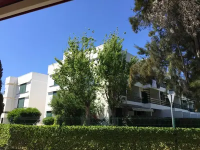 a white building with trees in front of it at Peixe and Barco Studio's in Vilamoura
