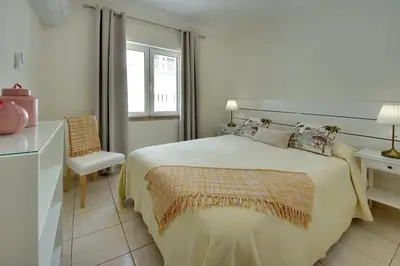 a white bedroom with a bed and a chair at Inn The Beach Apartments by Seareen in Albufeira
