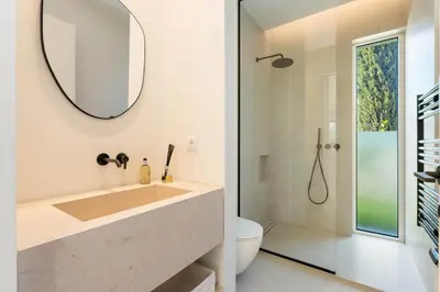 a bathroom with a sink and a toilet and a mirror at Modern Sea View Villa, Heated Pool,Rooftop Jacuzzi Outdoor Kitchen 12min faro Airport in Santa Bárbara de Nexe