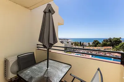 a table with an umbrella on a balcony with a pool at Studio avec vue mer et piscine Algarve Portugal in Albufeira