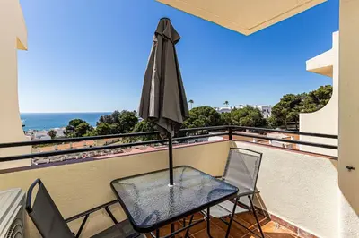 a table with an umbrella on a balcony at Studio avec vue mer et piscine Algarve Portugal in Albufeira