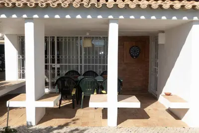 a porch of a house with chairs and a table at Casa do Cedro in Albufeira