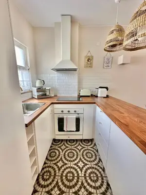 a kitchen with white cabinets and a wooden counter top at Solar Home appartement T2 in Albufeira