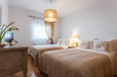 a bedroom with two beds and a table and a lamp at Casa da Praia in Albufeira