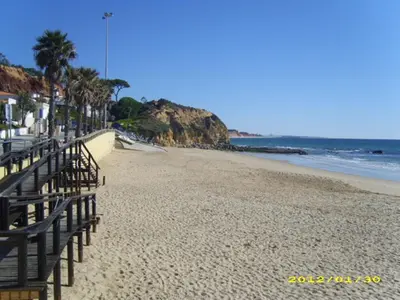 a sandy beach with a fence and the ocean at Casa da Praia in Albufeira