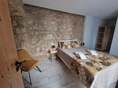 a bedroom with a bed and a stone wall at RECANTO da FELICIDADE in Albufeira