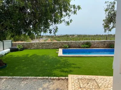 a yard with a swimming pool and green grass at Casa Herdeiro in Faro