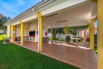 a large covered patio with yellow columns and grass at Apart Encosta S Jose - Piscina - Estacionamento in Guia