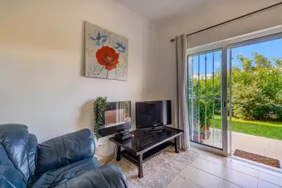 a living room with a couch and a television at Apart Encosta S Jose - Piscina - Estacionamento in Guia