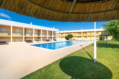 a resort with a swimming pool and a building at Apart Encosta S Jose - Piscina - Estacionamento in Guia