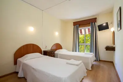 a hotel room with two beds and a window at Residencial Capri by Umbral in Albufeira