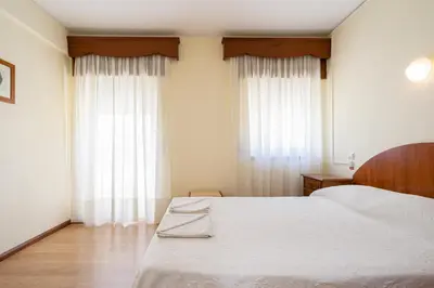 a bedroom with a white bed and a large window at Residencial Capri by Umbral in Albufeira