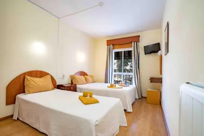 a hotel room with two beds and a window at Residencial Capri by Umbral in Albufeira