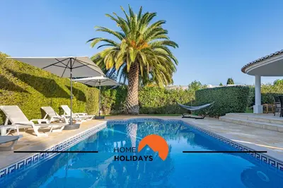 a swimming pool with chairs and a palm tree at #239 Vivenda V3 com Piscina by Home Holidays in Albufeira