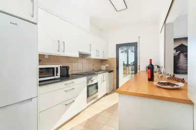 a kitchen with white cabinets and a wooden counter top at Host Wise - Serene Spacious House - Swimming Pool & Garden in Olhos de Água