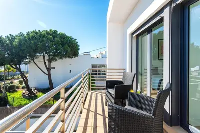 a balcony with two chairs and a laptop on it at Host Wise - Serene Spacious House - Swimming Pool & Garden in Olhos de Água