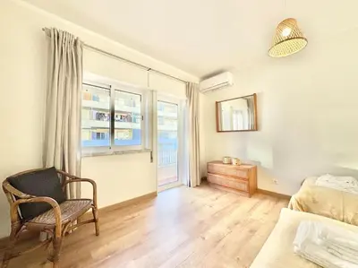 a bedroom with a bed and a chair and a window at Sea Front 180º View with AC and WiFi in Quarteira