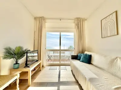 a living room with a couch and a large window at Direct Beach Access with Sea View, AC & WiFi in Quarteira
