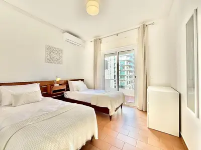a hotel room with two beds and a window at Direct Beach Access with Sea View, AC & WiFi in Quarteira