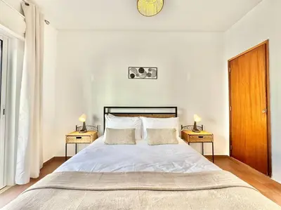 a bedroom with a large bed with two night stands at Direct Beach Access with Sea View, AC & WiFi in Quarteira