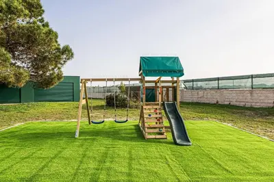 a playground with a slide on a grass field at Quinta dos Figos - Jacuzzi Perto da Praia in Guia