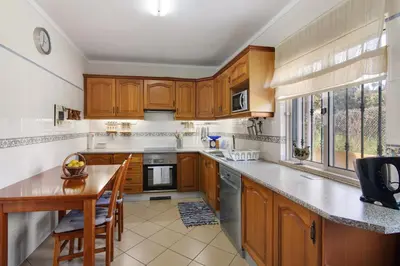 a kitchen with wooden cabinets and a table and chairs at Casa das Buganvilias in Loulé