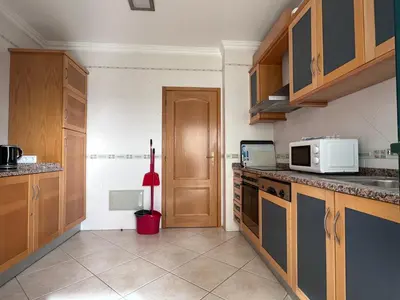 a kitchen with wooden cabinets and a white microwave at Oceanview Bliss in Albufeira Retreat Over Oldtown in Albufeira