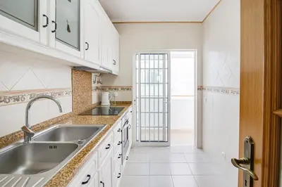 a kitchen with white cabinets and a sink at Cozy Apt 5min Beach Ocean View AC Wi Fi in Albufeira