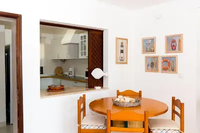 a kitchen and dining room with a wooden table and chairs at The Albufeira Concierge - Villa Praia São Rafael in Albufeira