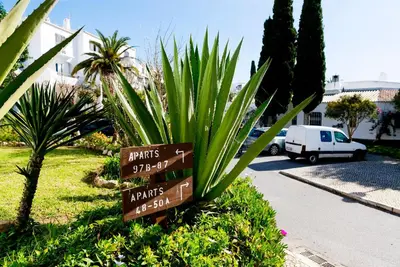 a sign in a yard with a plant and a street at The Albufeira Concierge - Villa Praia São Rafael in Albufeira