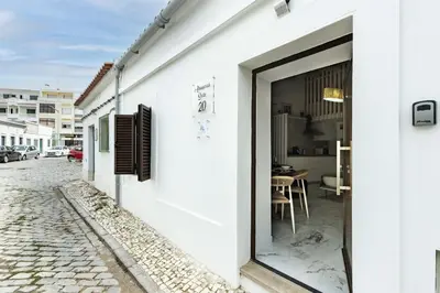 a white building with a large window on a street at Alcaçarias Suite 20 in Faro