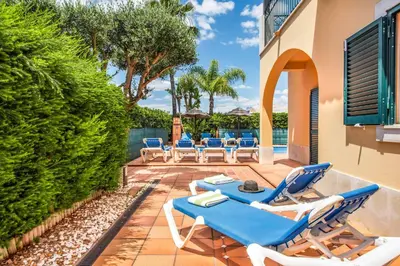a patio with blue and white lounge chairs and a pool at Villa Norcas Grande in Galé