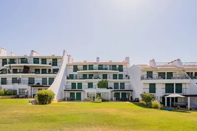 a large white apartment building with a grass yard at 2 bedroom apt Vila Sol in Quarteira