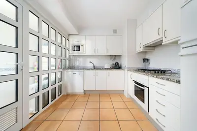 a kitchen with white cabinets and a tile floor at 2 bedroom apt Vila Sol in Quarteira