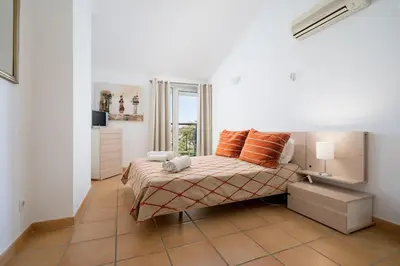 a bedroom with a bed with orange pillows on it at 2 bedroom apt Vila Sol in Quarteira
