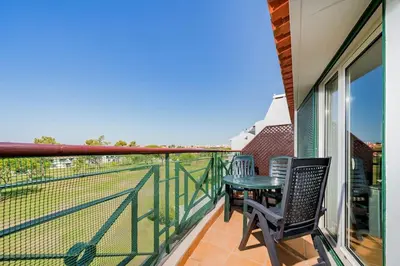 a balcony with a table and chairs and a tennis court at 2 bedroom apt Vila Sol in Quarteira