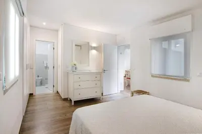 a white bedroom with a bed and a bathroom at Pear Tree Villa in Vale do Lobo