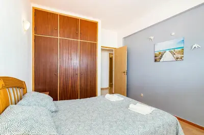 a bedroom with a bed and a wooden cabinet at TAC - Sunrise Montechoro Albufeira in Albufeira