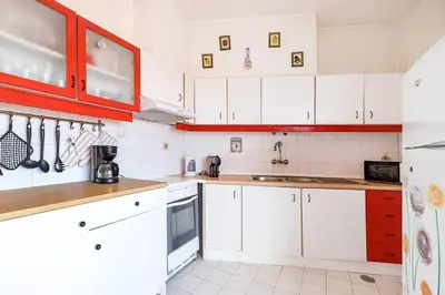a kitchen with white cabinets and red accents at TAC - Sunrise Montechoro Albufeira in Albufeira