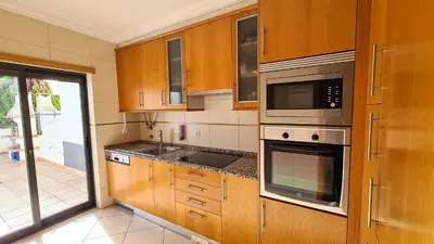 a kitchen with wooden cabinets and a sink and microwave at Charming 3-Bedroom Villa with Pool in Albufeira in Albufeira