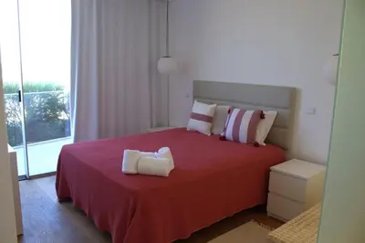 a bedroom with a bed with a redspread and a window at Lakes 24 - Av Praia da Falésia in Quarteira