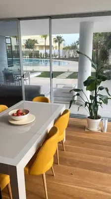 a dining room with a white table and yellow chairs at Lakes 24 - Av Praia da Falésia in Quarteira