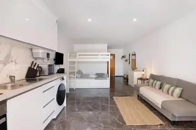 a kitchen and a living room with a couch and a table at Magnificent Beach Apartment in Albufeira