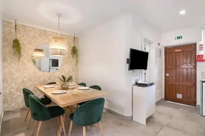 a dining room with a wooden table and green chairs at Stunning Modern Apartment In Oura in Albufeira