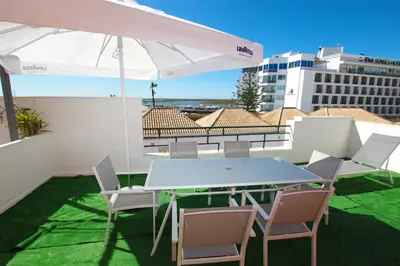 a table and chairs on a balcony with an umbrella at Marimar Sea View Apartment Faro in Faro