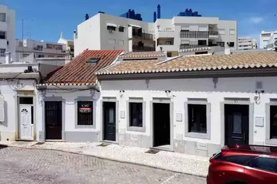 a white building with a red car parked in front of it at Faro old town cosy typical house in Faro